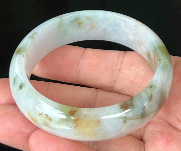 Close-up of red and moss green hues on icy apple green jadeite bangle