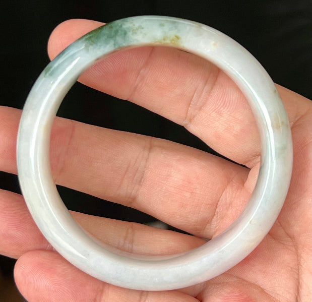 Close-up of red and moss green hues on icy apple green jadeite bangle