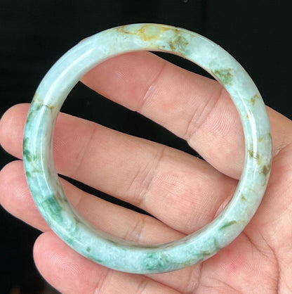 Close-up of imperial green and honey hues on icy milky white jadeite bangle