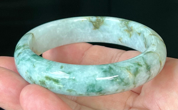 Close-up of imperial green and honey hues on icy milky white jadeite bangle
