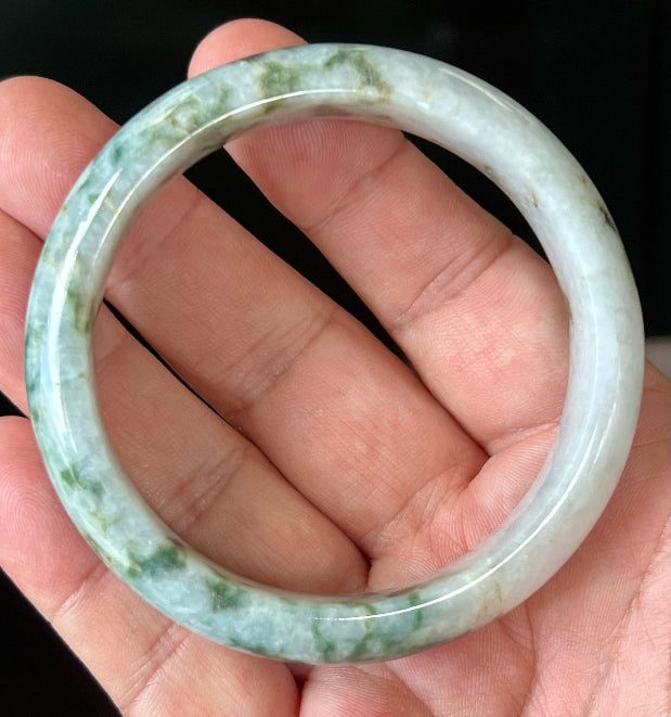 Close-up of imperial green and honey hues on icy milky white jadeite bangle