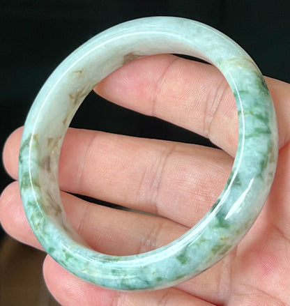 Close-up of imperial green and honey hues on icy milky white jadeite bangle