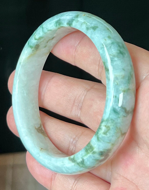 Close-up of imperial green and honey hues on icy milky white jadeite bangle