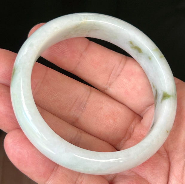 Close-up of moss and apple green hues on icy milky white jadeite bangle