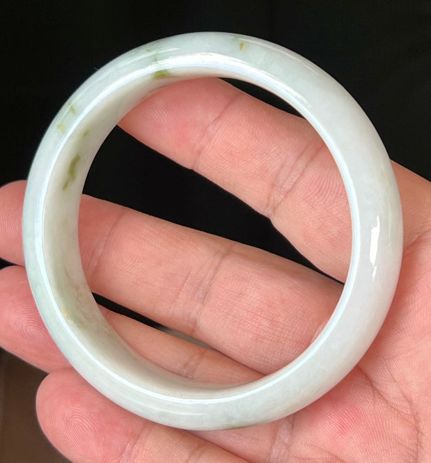 Close-up of moss and apple green hues on icy milky white jadeite bangle