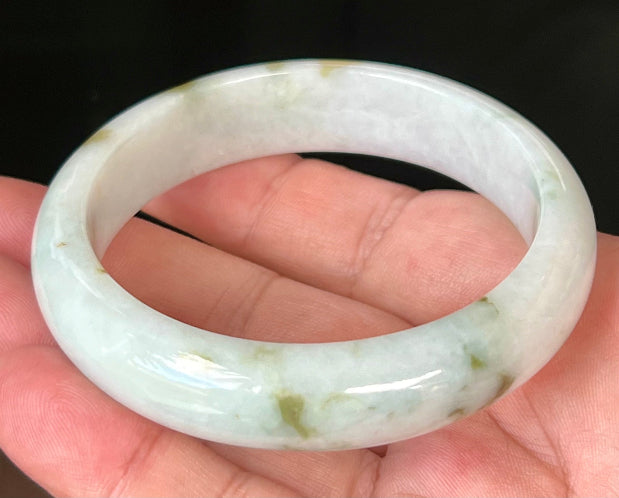 Close-up of moss and apple green hues on icy milky white jadeite bangle