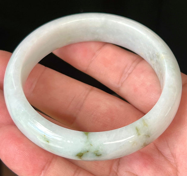 Close-up of moss and apple green hues on icy milky white jadeite bangle