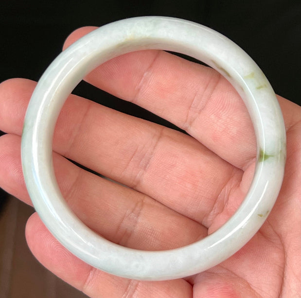 Close-up of moss and apple green hues on icy milky white jadeite bangle
