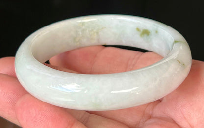 Close-up of moss and apple green hues on icy milky white jadeite bangle