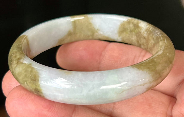Close-up of golden brownish moss green hues on icy milky white jadeite bangle