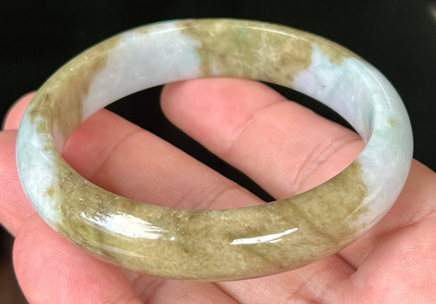 Close-up of golden brownish moss green hues on icy milky white jadeite bangle