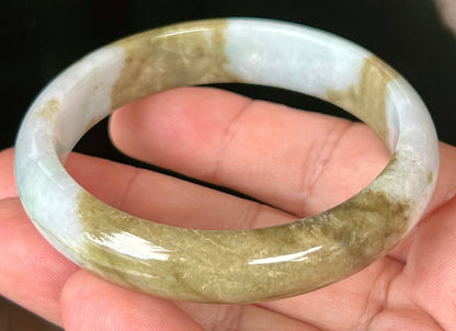 Close-up of golden brownish moss green hues on icy milky white jadeite bangle