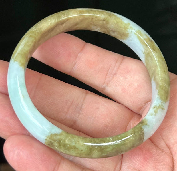Close-up of golden brownish moss green hues on icy milky white jadeite bangle