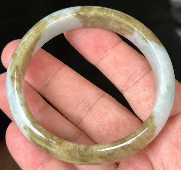 Close-up of golden brownish moss green hues on icy milky white jadeite bangle