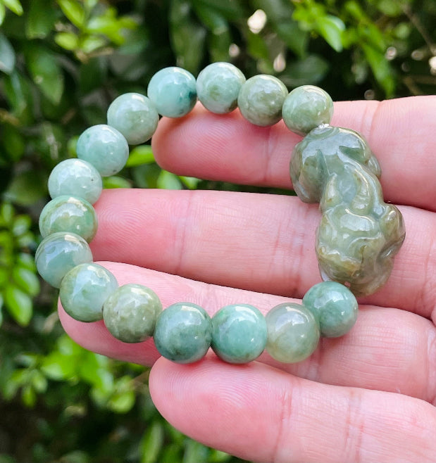 Handcrafted genuine Grade A Burmese jadeite stretch bracelet showcasing beautiful mossy green beads with a hand-carved Pixiu pendant and official certification