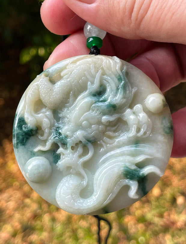 Close-up of a natural Grade A certified Burmese jadeite pendant featuring green and milky white hues hand-carved with a dragon motif, item JP082