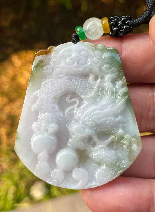 Close-up of a natural Grade A certified Burmese jadeite pendant featuring milky white, green, and golden brown hues hand-carved with a dragon motif, item JP081