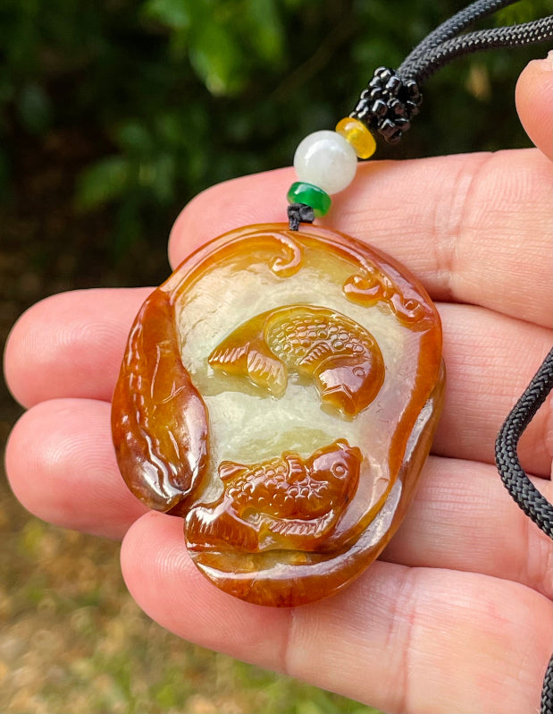 Handcrafted genuine Grade A certified Burmese jadeite amulet with orange and olive green colors representing warmth and prosperity