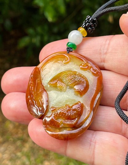Handcrafted genuine Grade A certified Burmese jadeite amulet with orange and olive green colors representing warmth and prosperity
