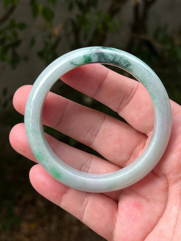 Close-up of moss in snow and emerald green patterns on icy green jadeite bangle