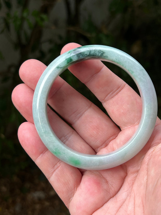 Close-up of moss in snow and emerald green patterns on icy green jadeite bangle