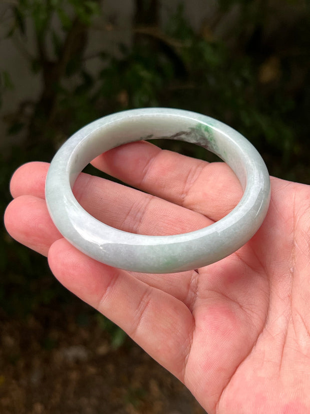 Close-up of moss in snow and emerald green patterns on icy green jadeite bangle