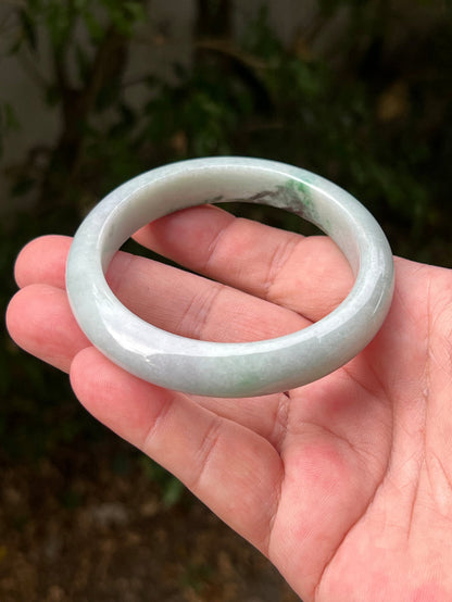 Close-up of moss in snow and emerald green patterns on icy green jadeite bangle