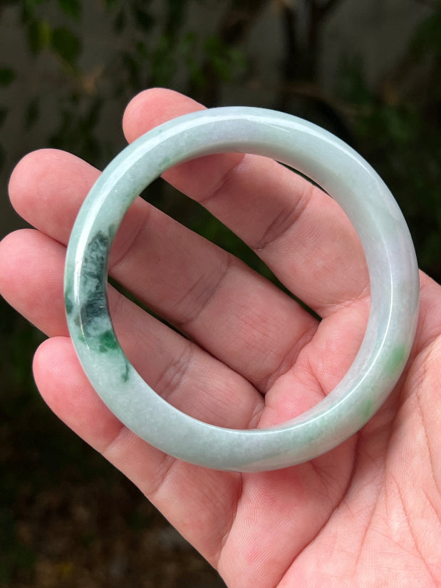Close-up of moss in snow and emerald green patterns on icy green jadeite bangle