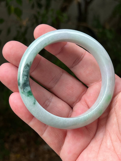Close-up of moss in snow and emerald green patterns on icy green jadeite bangle