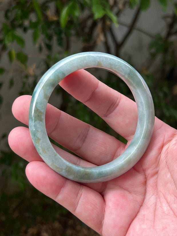 Close-up of natural moss green cloud formations on icy seafoam jadeite bangle