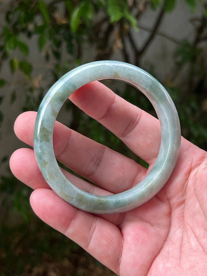 Close-up of natural moss green cloud formations on icy seafoam jadeite bangle