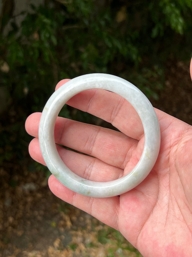 Close-up of pale celadon green highlights on icy milky white jadeite bangle