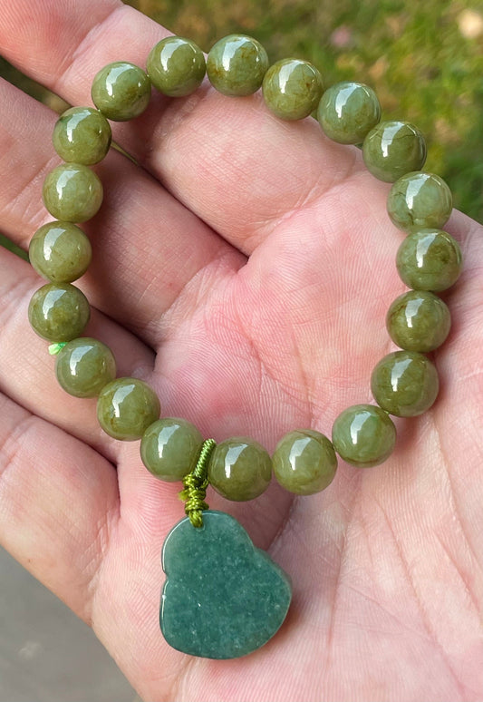 9mm natural Type A Burmese jade beads showing earthy olive green hues and a hand-carved Laughing Buddha pendant on the wrist