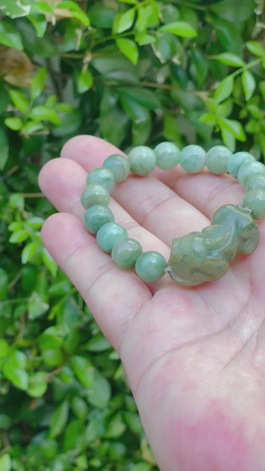 Video showcasing the vitreous luster, mossy green hue, and hand-carved Pixiu pendant of the 10mm certified Burmese jade bead bracelet JBB164