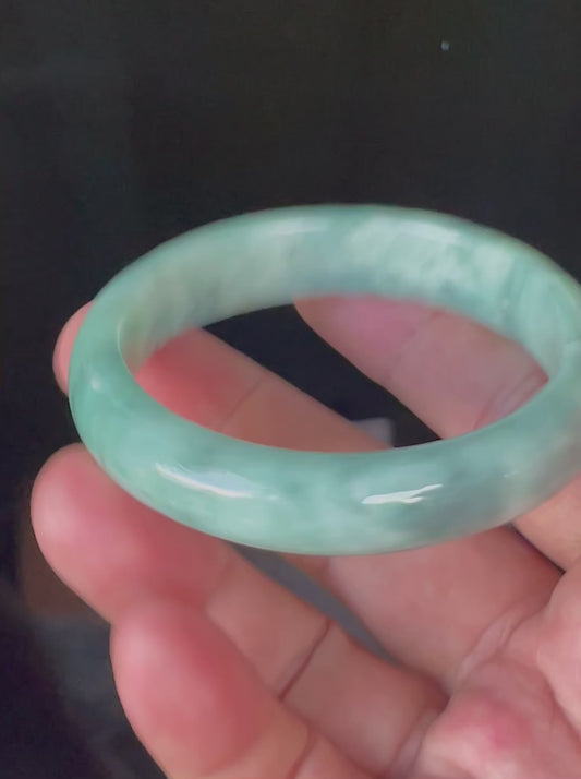 Video showcasing the bright glassy luster and moss in the snow pattern of icy imperial green, apple green, and milky white Burmese jadeite bangle JB914