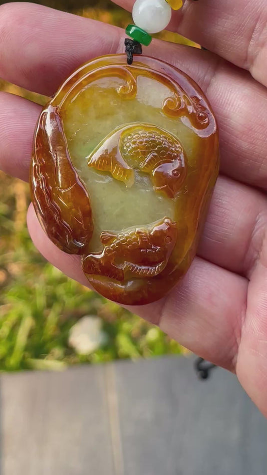 Video showcasing the vitreous luster, orange and olive green hues, and hand-carved twin fish motif of the certified Burmese jade pendant JP080