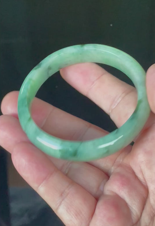 Video showcasing the bright glassy luster and floral moss in the snow effect of icy apple green, imperial green, black, and greyish milky white Burmese jadeite bangle JB911