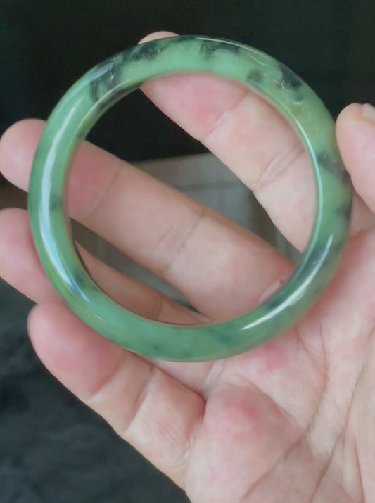 Video showcasing the bright glassy luster and black floral design of icy apple green Burmese jadeite bangle JB905
