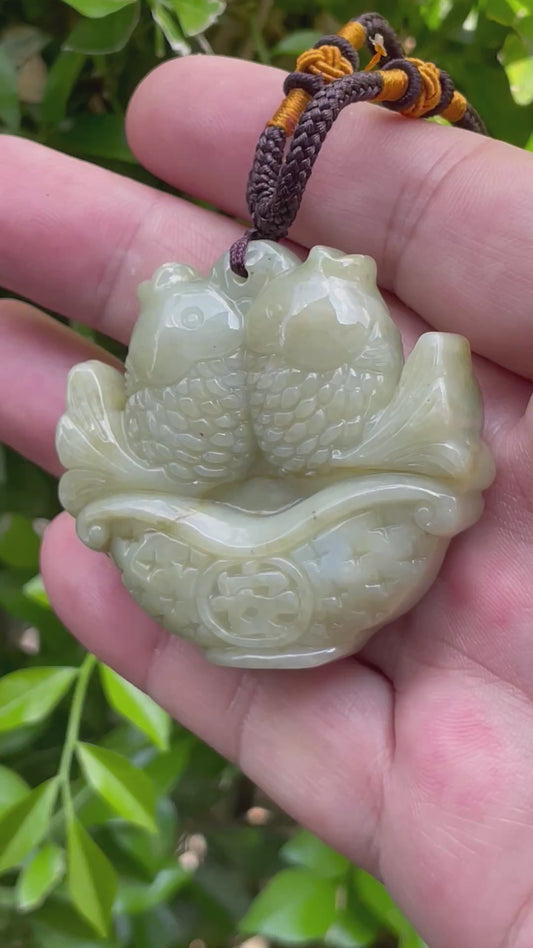Video showcasing the glossy translucency, icy apple and olive green hues, and hand-carved twin fish in treasure basin motif of the certified Burmese jade pendant JP038