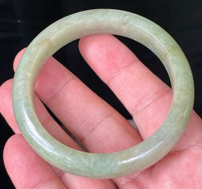 Flat inner and round outer edges of 58.5mm icy apple green, white, and honey Burmese jade bangle JB212