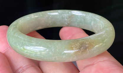 Flat inner and round outer edges of 58.5mm icy apple green, white, and honey Burmese jade bangle JB212
