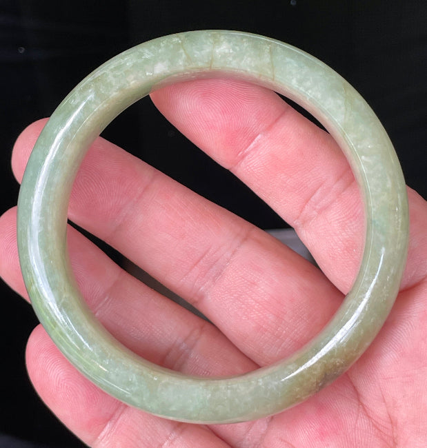 Flat inner and round outer edges of 58.5mm icy apple green, white, and honey Burmese jade bangle JB212