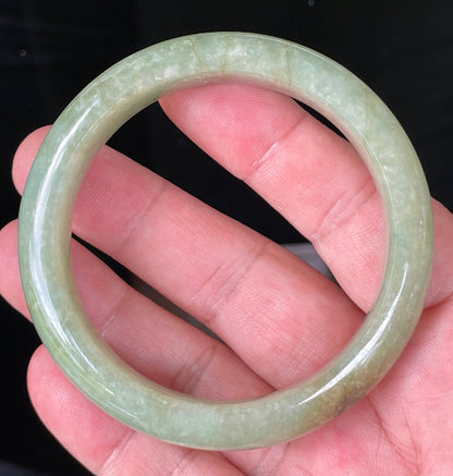 Flat inner and round outer edges of 58.5mm icy apple green, white, and honey Burmese jade bangle JB212