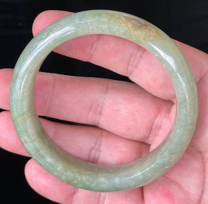 Flat inner and round outer edges of 58.5mm icy apple green, white, and honey Burmese jade bangle JB212