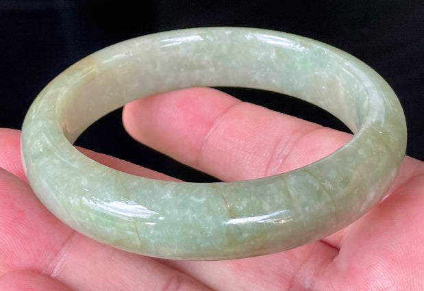Flat inner and round outer edges of 58.5mm icy apple green, white, and honey Burmese jade bangle JB212