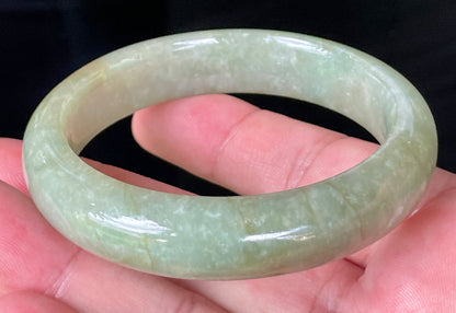 Flat inner and round outer edges of 58.5mm icy apple green, white, and honey Burmese jade bangle JB212